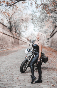 漂亮的骑摩托车的女人在户外摆姿势。