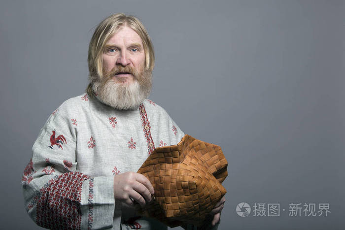 斯拉夫长胡子的人,穿着一件漂亮的彩绘衬衫和一顶桦树皮帽子照片-正版