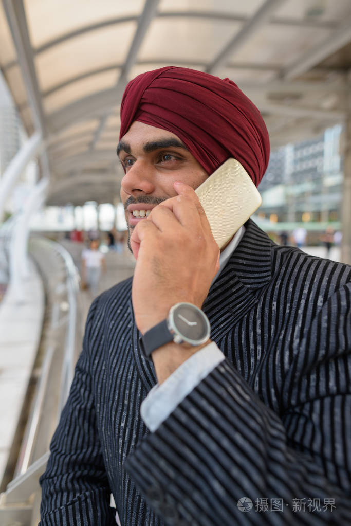 印度商人与头巾在城市的户外谈论电话