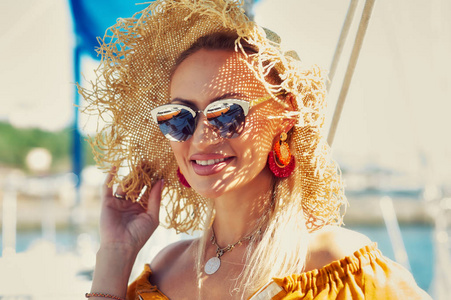 一位年轻女子在游艇上休息的肖像。 女孩穿着一件亮黄色的衣服，戴着时髦的太阳镜