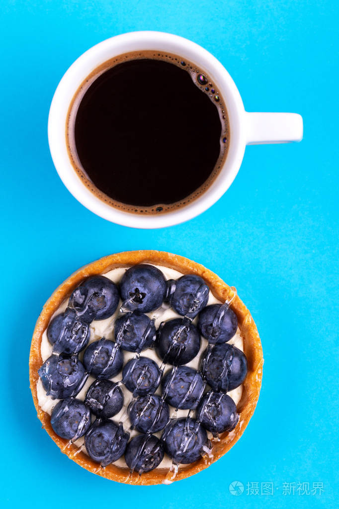 美味的蓝莓酒石香草奶油和鲜杯咖啡在明亮的蓝色背景复制空间顶部视图