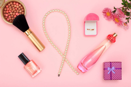 礼品盒珠瓶香水指甲油和金环在盒粉与刷子在粉红色背景。 女性香水，化妆品和配件。 上面的风景。