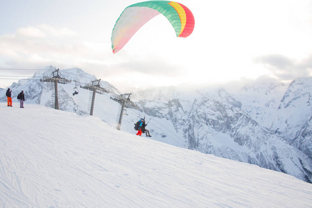 滑翔伞有两个人，一个教练和一个乘客在雪山上飞翔