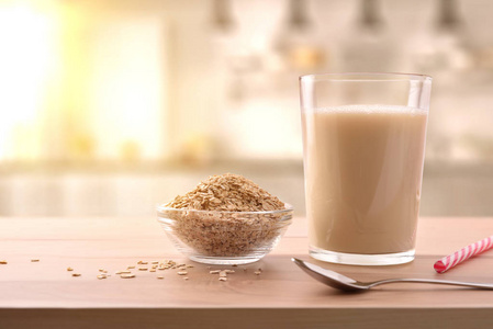 燕麦饮料在玻璃和麦片片在厨房的长凳上。 水平构图。 正面视图
