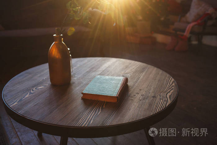 咖啡桌花瓶与一枝和旧书在阳光下