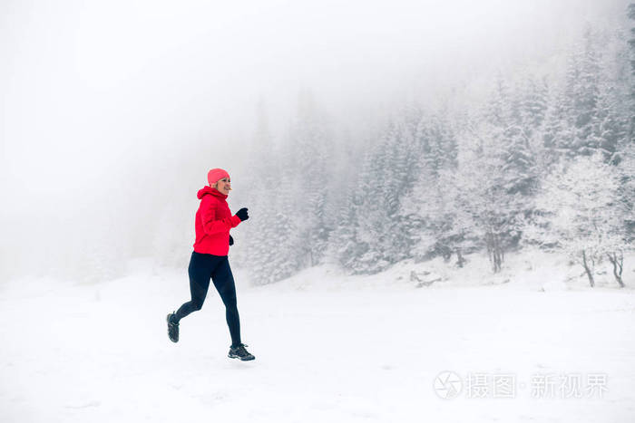 年轻快乐的女孩运动员在下雪的冬天工作. 女跑步者在户外慢跑.