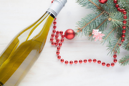 圣诞树附近的一瓶葡萄酒，白色木制背景的新年玩具