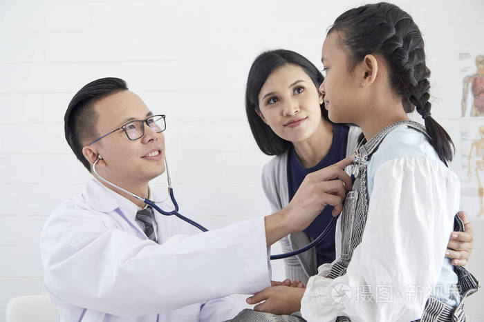 医生用听诊器听生病男孩的肺. 他和他母亲一起去看医生.