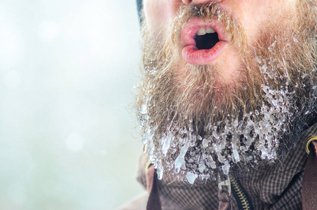 运动后，有胡子的年轻人在街上被冰柱和冰冻的水滴覆盖。 冬季口腔蒸发