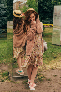 一个浪漫的女孩在城市里穿着一件衣服和一件暖色的毛衣，她的头发在风中发展。 微笑和头晕。 戴上帽子