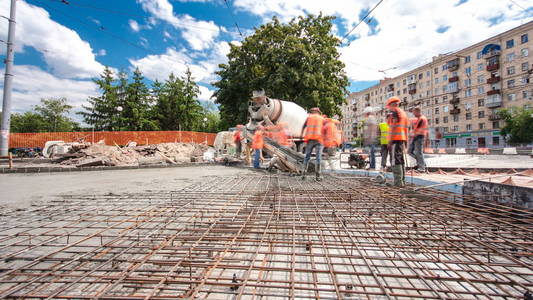 混凝土工程的道路建设与许多工人和搅拌机时间推移超移。 将砂浆浇注到金属钢筋上。 重建电车轨道