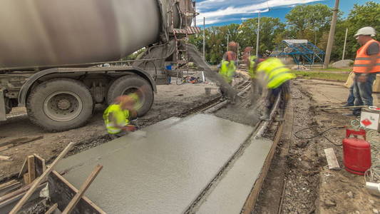 混凝土工程的道路建设与许多工人和搅拌机时间推移超移。 将砂浆浇注到金属钢筋上。 重建电车轨道