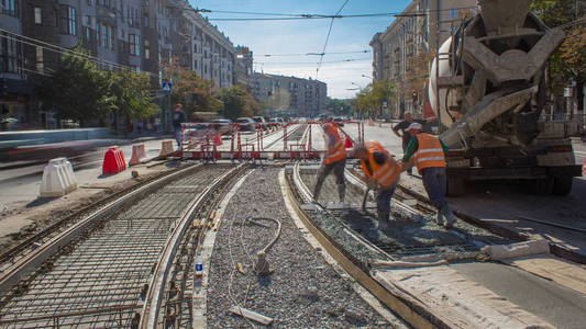 混凝土工程的道路建设，许多工人在统一和搅拌机时间推移。 重建电车轨道