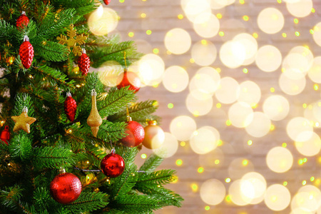 装饰圣诞树上的软黄灯与博克效应背景。 节日构图与冷杉和模糊闪闪发光的背景新年假期装饰。 关闭复制空间。