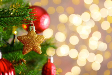 装饰圣诞树上的软黄灯与博克效应背景。 节日构图与冷杉和模糊闪闪发光的背景新年假期装饰。 关闭复制空间。