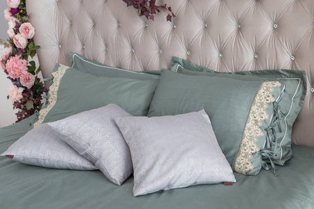 时尚的卧室室内设计，床上有白色和灰色枕头。 家庭室内设计真实照片。
