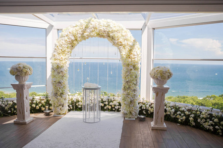白色婚礼装饰室内。 白色婚礼拱门，地板上有花和白色地毯。
