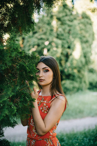 美丽的年轻女孩在夏天红色礼服在公园里