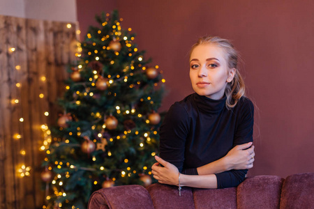 美丽的年轻女子，长长的金发站在圣诞树旁边。 圣诞魅力照片