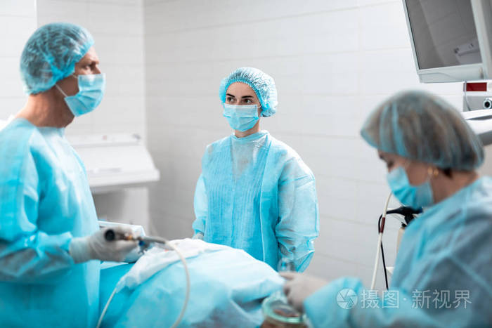 年轻护士在外科手术中戴保护面罩看外科医生照片 正版商用图片150bjq 摄图新视界