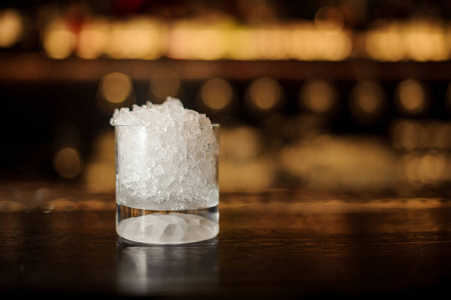在模糊的灯光背景下, 酒吧柜台上有冰块的玻璃