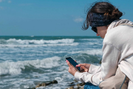 秋天, 女人坐在海边的电话里打着一条信息