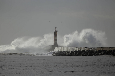 海浪飞溅。河口码头和灯塔，维拉多孔德，葡萄牙北部。