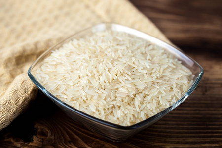 白色米饭种子在玻璃碗上的木桌配料烹饪。