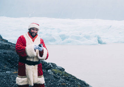 传统的正宗风格圣诞老人拿着手机，在冰岛冰川附近大笑
