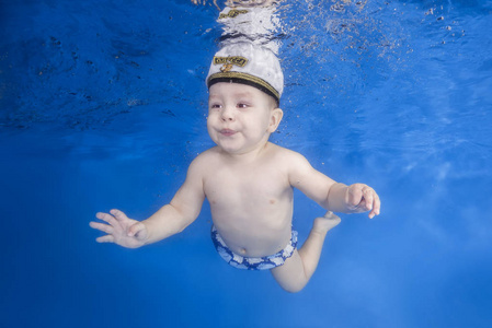 男孩在蓝色的水背景下在游泳池里游泳。 健康的家庭生活方式和儿童水上运动活动。 儿童发展疾病预防