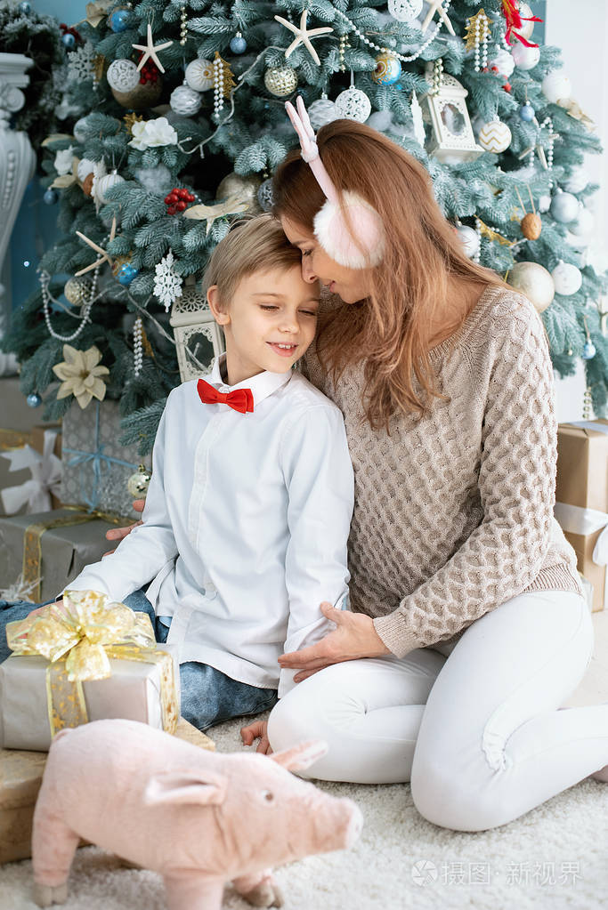 照片 妈妈和儿子在圣诞树下. 微笑的母亲送圣诞礼物给她的儿子.