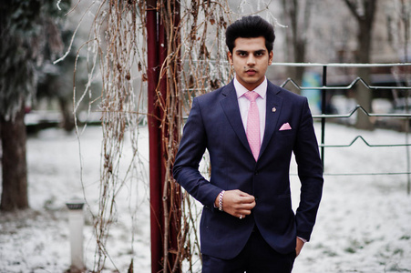 优雅的印度男子男子模特穿着西装和粉红色领带在冬日摆好姿势。