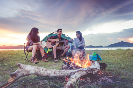 一群旅行者一起露营，一起野餐，一起演奏音乐。 山和湖的背景。 人和生活方式。 户外活动和休闲主题。 背包客和徒步旅行者。 黎明和
