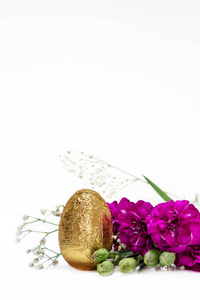 金蛋和白色背景上的紫红色花朵。