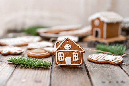 可爱的小房子在前景。棕色木桌上有很多不同形式的姜饼。装饰有白色的甜釉。圣诞节的心情, 冬天的早晨。冷杉分枝