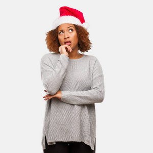戴着圣诞老人帽子的年轻黑人女士想着一个想法