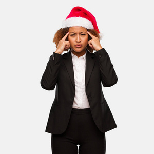 年轻的商界黑人妇女戴着圣诞圣诞老人帽，做着集中注意力的手势