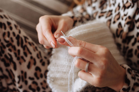 女人手织天然羊毛衣服。 针织针关闭。 横向照片。 自由职业创意工作。 手工艺概念