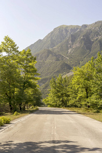 在阳光明媚的夏天观看农村狭窄的道路和山脉TzoumerkaEpirus希腊地区。