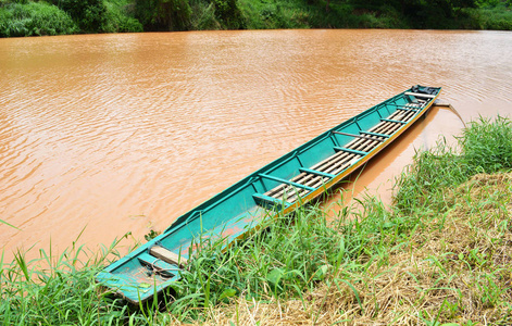 江边自然的旧木船水中浊河背景的老绿长渔船