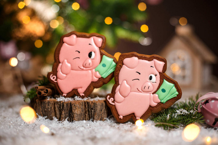 假日传统食品面包店。 姜饼两只幸运的粉红色猪，带着一捆钱，在舒适的温暖装饰和花环灯。
