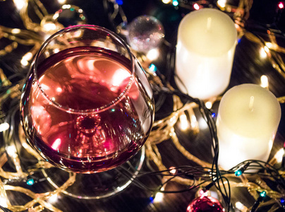 明亮的圣诞节背景蜡烛和球在圣诞花环白兰地玻璃关闭。 波克效应