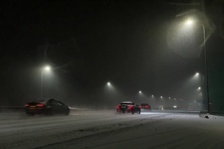 夜间下雪时，汽车在路上行驶