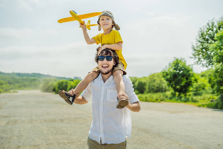 快乐的父子在旧跑道背景下玩玩具飞机。 和孩子们一起旅行的概念。