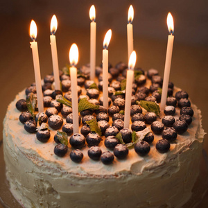 生日蛋糕一个白色的大生日蛋糕,上面有新鲜的有机蓝莓,薄荷和白色蜡烛