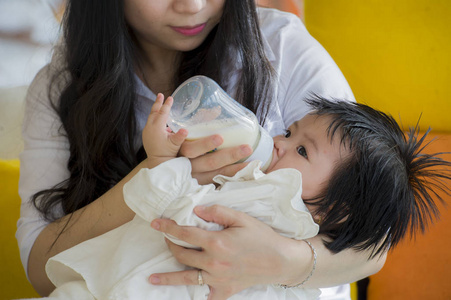 生活方式坦率的肖像年轻，快乐和甜蜜的亚洲日本妇女喂养她美丽的女婴与配方瓶在度假村作为母亲护理女儿关心和爱