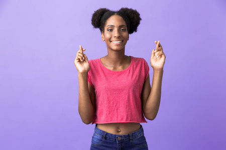 照片中年轻的非洲裔美国妇女微笑着，手指在紫色背景下交叉