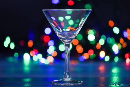 鸡尾酒玻璃在不集中的花环五颜六色的灯光。圣诞晚会上喝什么。冬季派对的酒精鸡尾酒。鸡尾酒理念。冬季酒精鸡尾酒饮料的简单食谱