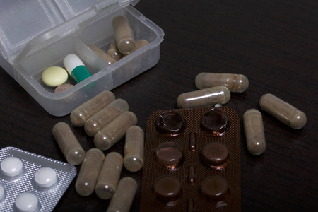 桌子上的药片和水泡。 一些开始了。 附近有几片药丸。 在黑暗的背景上。