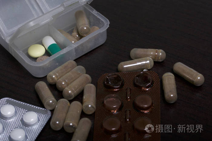 桌子上的药片和水泡. 一些开始了. 附近有几片药丸. 在黑暗的背景上.